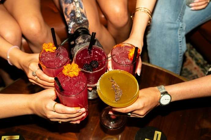 Friends toast with colorful cocktails.